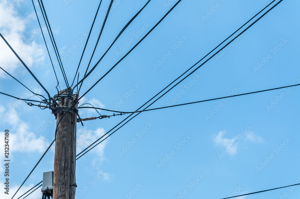 Old retro style wooden pole with many electric supply wires or cables against blue sky. Power line. Old retro style wooden pole with many electric supply wires or cables against blue sky. Power line.