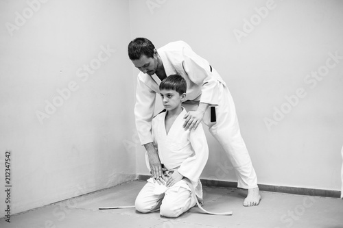 A boy in a kimono has an aikido training with a coach