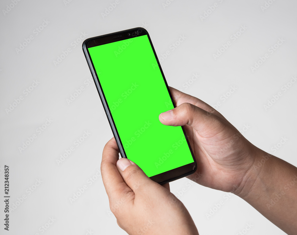 Human hand holding blank mobile smartphone on gray background Human hand holding blank mobile smartphone on gray background