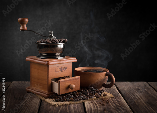 Coffee grinder with coffee cup on wood,dark background
