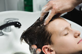 a boy is washed by the hairdresser in the barbershop