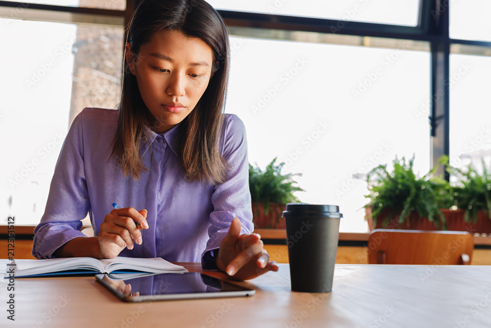 Young woman sitting at cafe and reading on digital tablet Young woman sitting at cafe and reading on digital tablet
