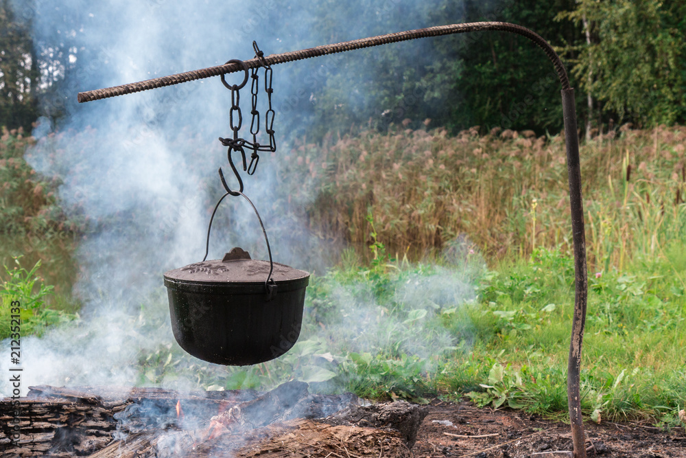 A food pot hangs over a burning fire in the nature
A food pot hangs over a burning fire in the nature