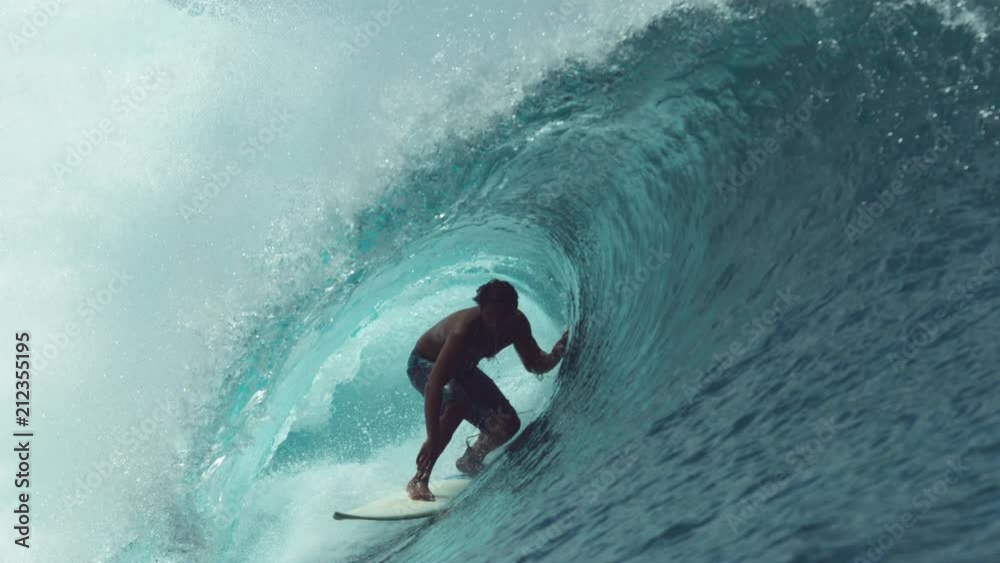 SLOW MOTION, CLOSE UP: Extreme sportsman having fun riding a beautiful barrel ocean wave. Breathtaking shot of active man on holiday surfing a perfect crystal clear hollow wave in Teahupoo, Tahiti.