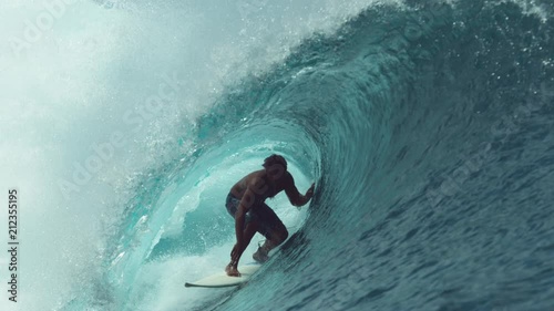 SLOW MOTION, CLOSE UP: Extreme sportsman having fun riding a beautiful barrel ocean wave. Breathtaking shot of active man on holiday surfing a perfect crystal clear hollow wave in Teahupoo, Tahiti. photo