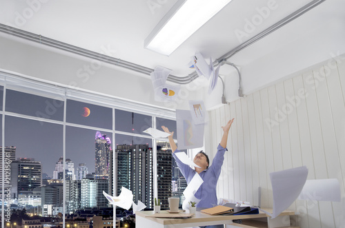 Successful business man tossing papers celebrating at the office and happy while celebrating success at their working places