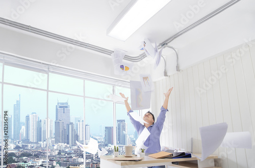 Fotografie Successful business man tossing papers celebrating at the office and happy while