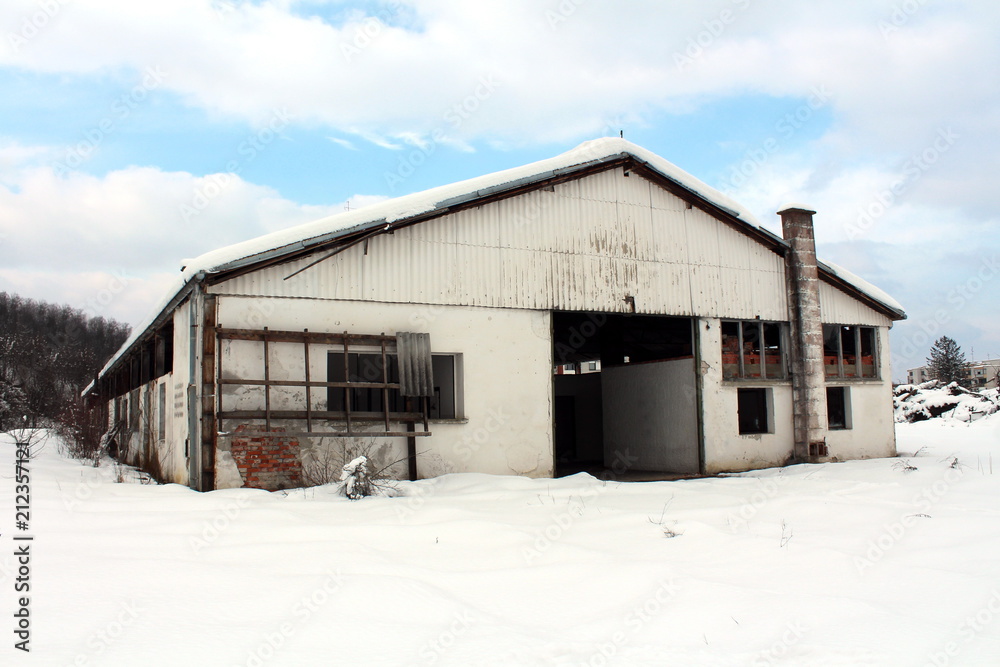Abandoned dilapidated vehicle repair and garage building with missing broken windows and doors covered in fresh snow on cold winter day Abandoned dilapidated vehicle repair and garage building with missing broken windows and doors covered in fresh snow on cold winter day