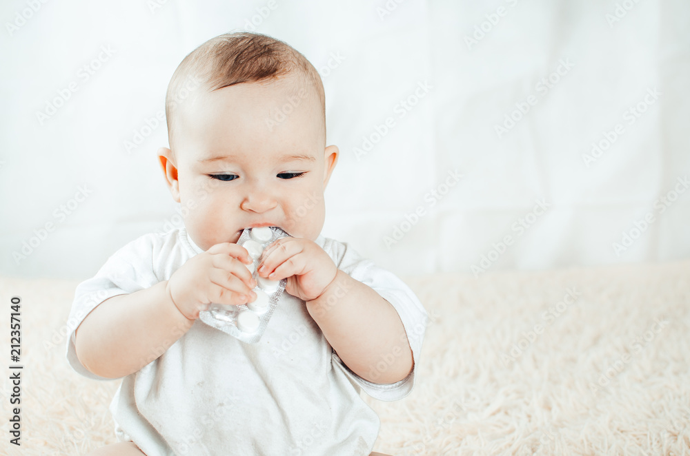 An infant plays with the pills on the bed An infant plays with the pills on the bed