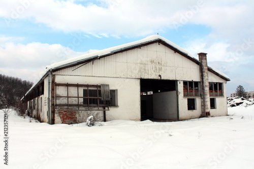 Abandoned dilapidated vehicle repair and garage building with missing broken windows and doors covered in fresh snow on cold winter day © hecos