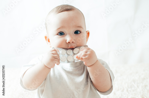 An infant plays with the pills on the bed photo