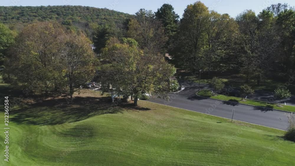 Drone Pulling Back And Increasing Alt Over Golf Course With White Car Driving Drone Pulling Back And Increasing Alt Over Golf Course With White Car Driving