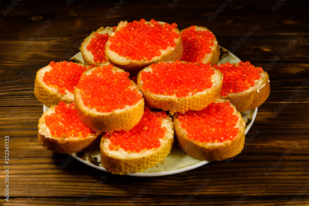 Sandwiches with red caviar on wooden table