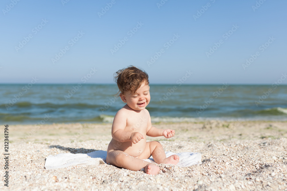 little child sitting on a towel by the sea naked cheerful and happy little child sitting on a towel by the sea naked cheerful and happy