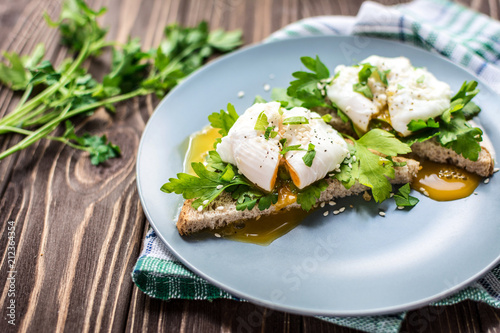 Homemade poached eggs on toast with fresh herbs and pepper