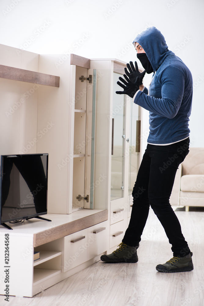Man burglar stealing tv set from house Man burglar stealing tv set from house