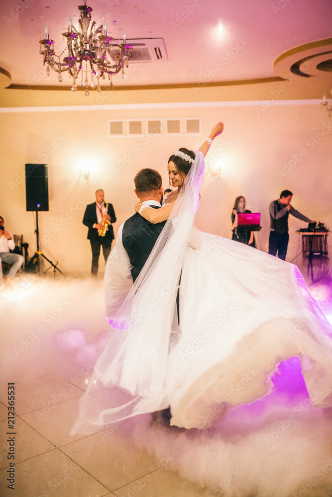 Happy newlyweds dancing in the restaurant hall. Bride and groom special moment in wedding day.