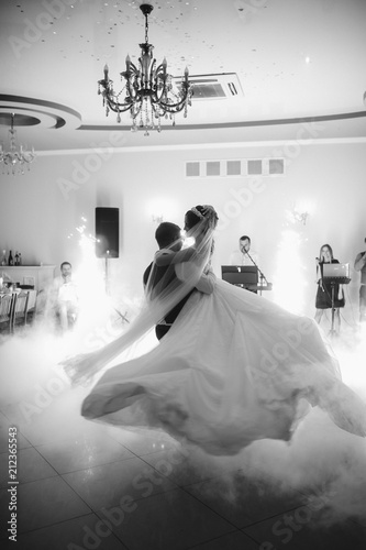 Obraz na płótnie Happy newlyweds dancing in the restaurant hall. Bride and groom special moment in wedding day. w salonie