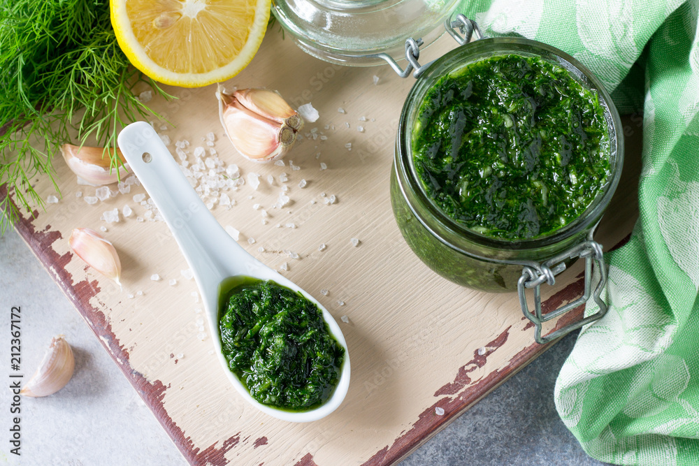 Preserving sauce dill with garlic and olive oil on the kitchen wooden background. Top view flat lay background, copy space. Preserving sauce dill with garlic and olive oil on the kitchen wooden background. Top view flat lay background, copy space.