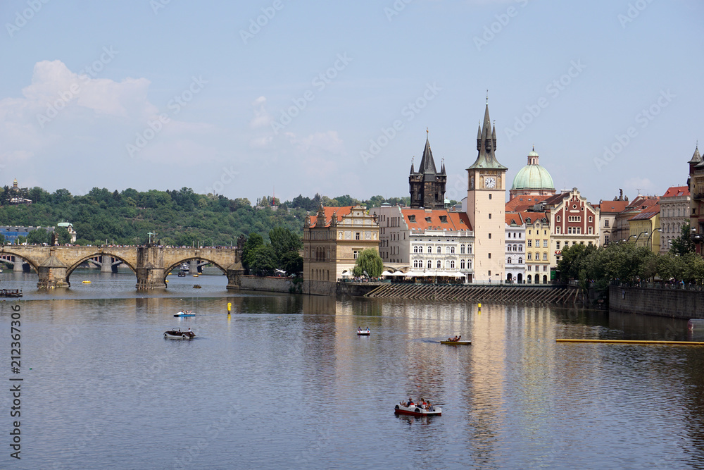 View of Charles Bridge, Old Town Water Tower reflected in the Vltava river with pedal boats, Prague, Czech Republic