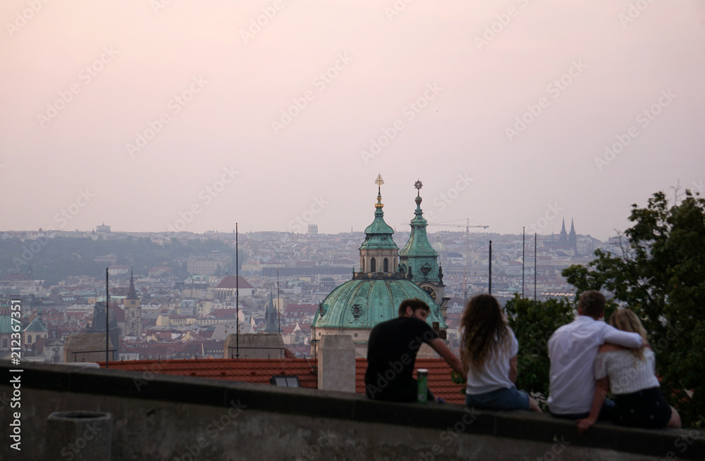 Obraz premium Young people admiring the panorama of Prague at dawn in front of the church of Saint Nicholas, Prague, Czech Republic