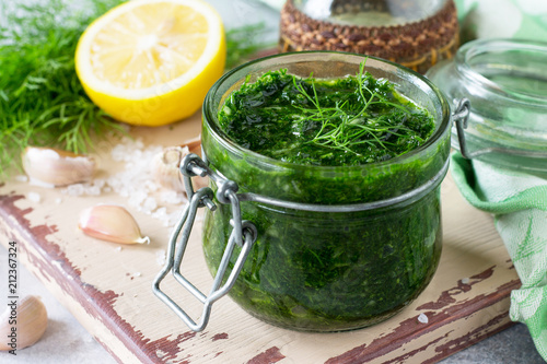 Preserving dill with garlic and olive oil on the kitchen wooden background.