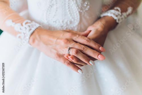 The hands of the bride wearing and corrects a gold wedding engagement ring with a diamond. Bride's Preparations. Wedding Morning. Jewelry. Manicure close up.