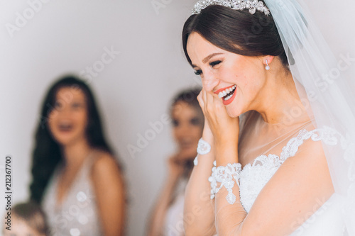Obraz na płótnie Happy bridesmaid hugging the bride in the bedroom in the morning