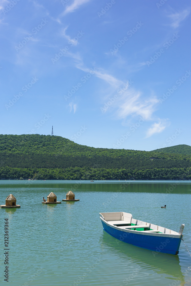 Bright blue empty rowing boat for riding on the green water of the mountain lake Abrau-Durso