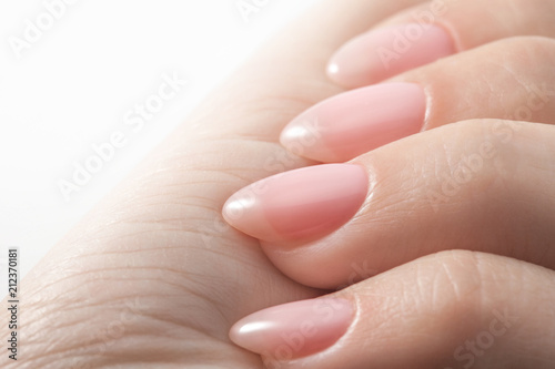 Women s hands with perfect Nude manicure. Nail Polish is a natural pale pink shade. Isolated on white