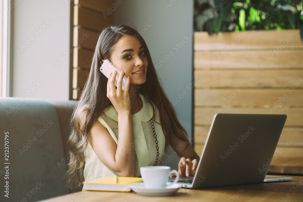 Beautiful girl working out a plan of the project and concept. Girl paints a website design on a laptop. student prints a message on the phone in the messenger. Development. Digital marketing