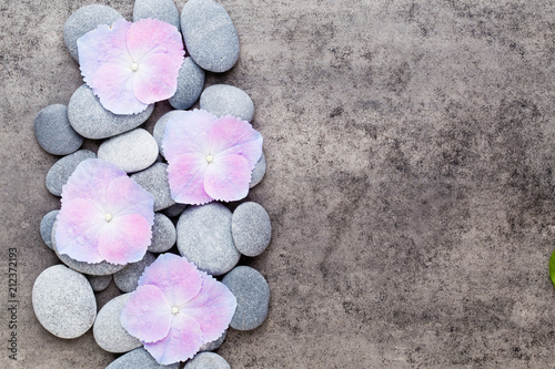Spa flowers and massage stone, on grey background.
