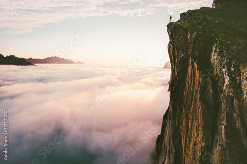 Canvastavla Traveler standing on cliff edge mountain top above sunset clouds travel adventur