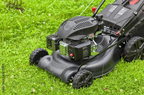 A four-stroke gasoline lawnmower on top of the grass in the garden