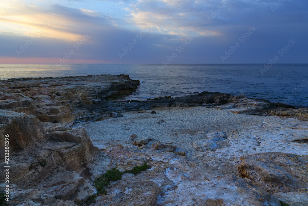 Rocks on shore of sea and the city of Hersonissos, Crete, Greece.