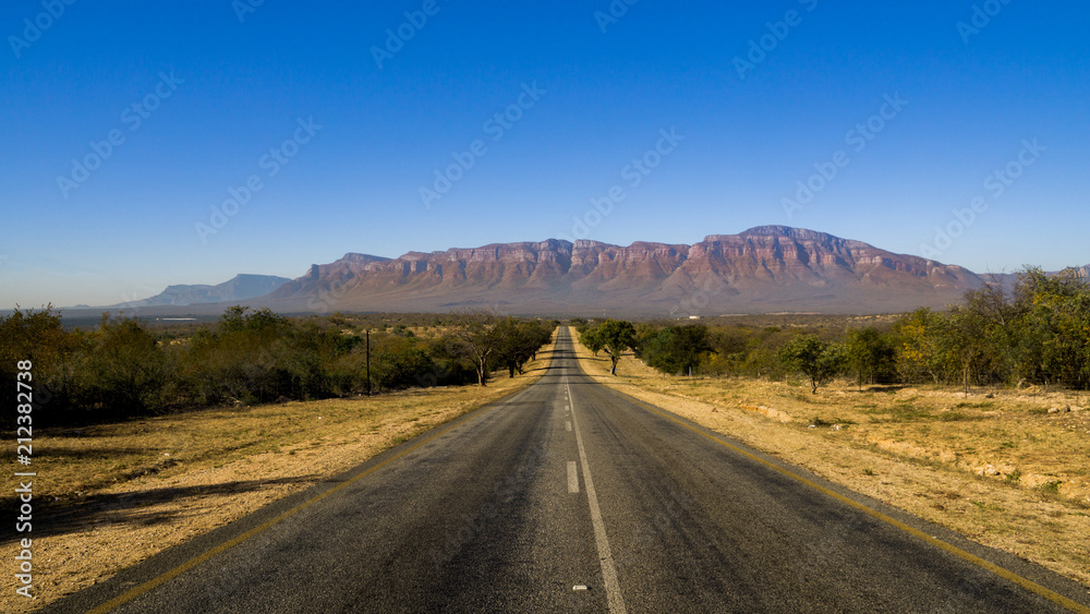 Two lane black top with mountains in the background in South Africa near Hoedspruit. 