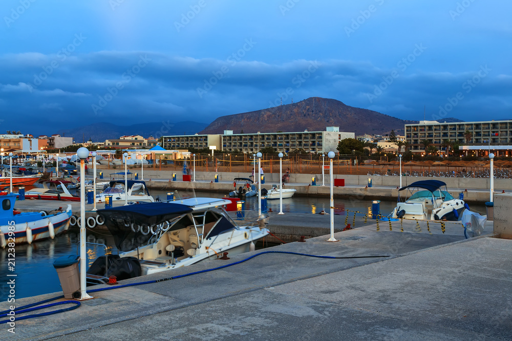 Beautiful sea with evening soft light of the sunset against cloudy sky with coastal line resort town, on Crete. Greece