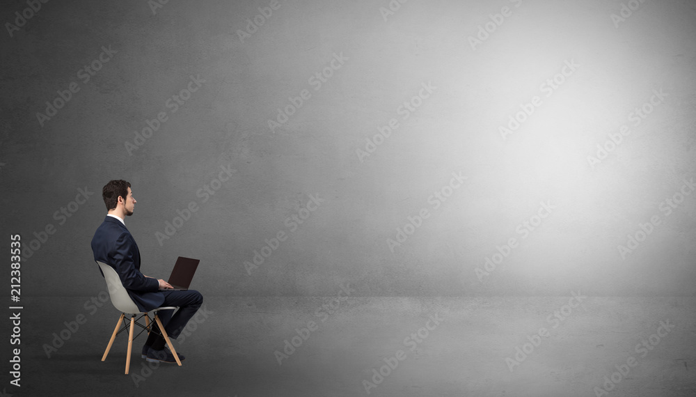 Businessman staying in an empty grey dark room with stuffs on his lap
Businessman staying in an empty grey dark room with stuffs on his lap