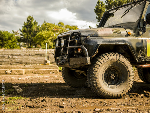 front view of massive 4x4 off-road car on the dirty ground panorama in mountains