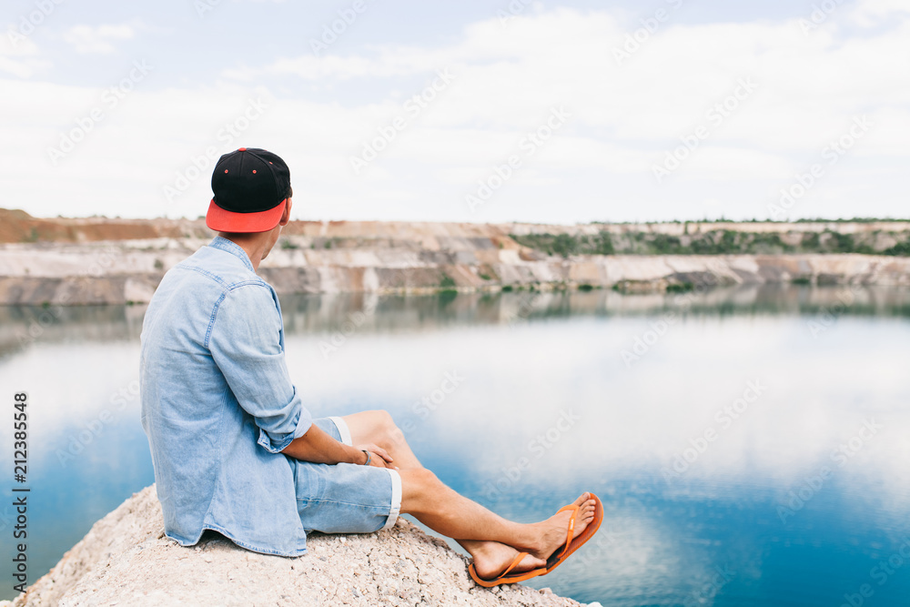Fototapeta premium Portrait of a man sitting on a rock, travel around the island, a tourist on vacation