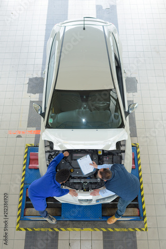 two mechanics repairing a car in a garage