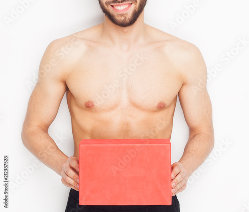 Cropped image of handsome romantic guy with a sports figure holding a present for his girlfriend on gray background