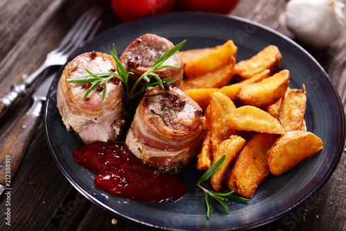 Meat chunks wrapped with bacon served with potato wedges