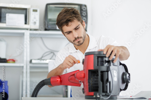 handsome young repairman fixing vacuum cleaner