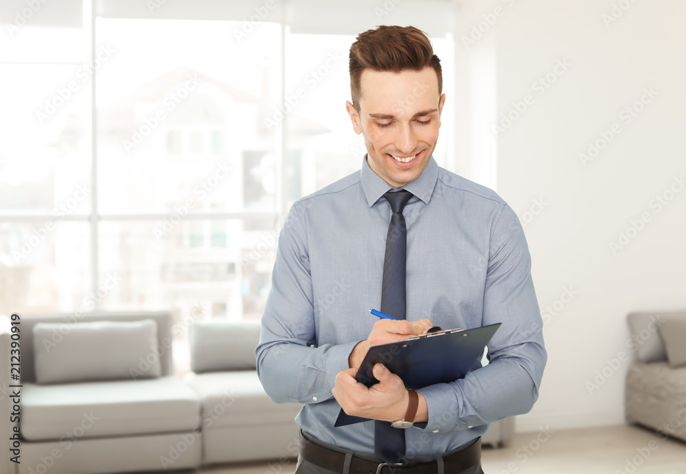 Fototapeta premium Male real estate agent with clipboard indoors