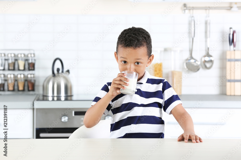 Adorable African-American boy with glass of milk in kitchen Adorable African-American boy with glass of milk in kitchen