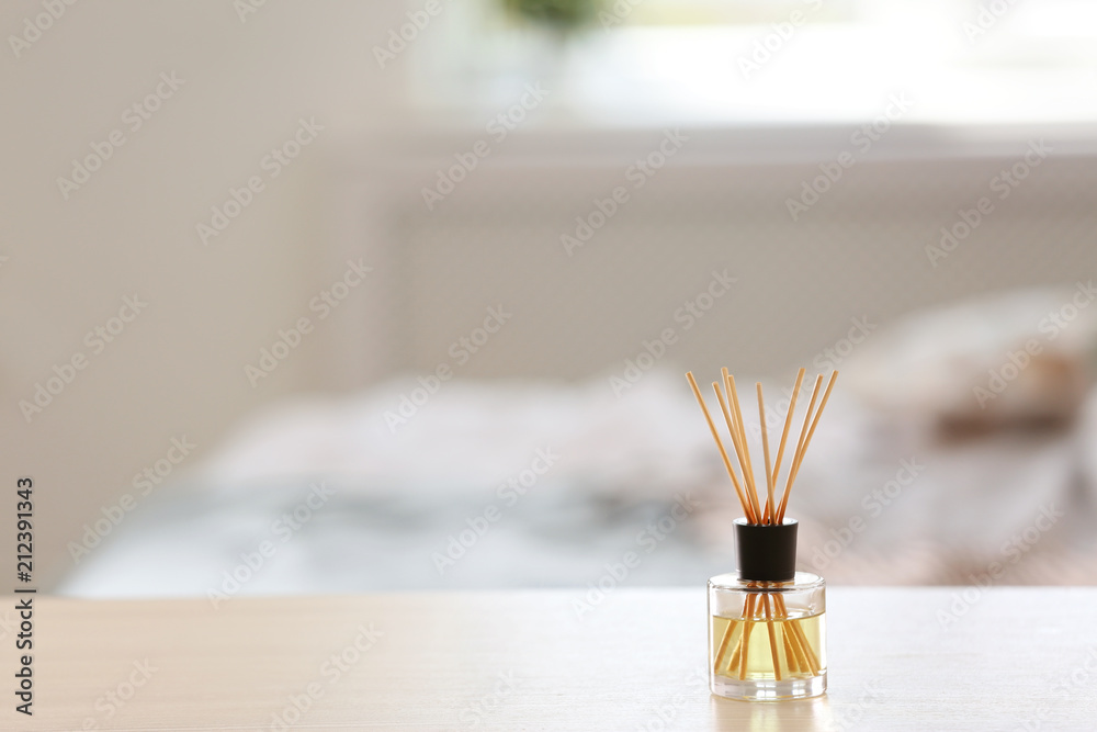 Fototapeta premium Aromatic reed air freshener on table against blurred background