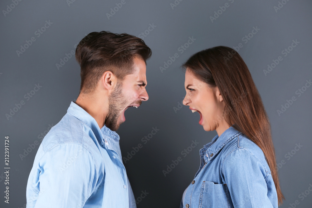 Young couple having argument on grey background. Relationship problems