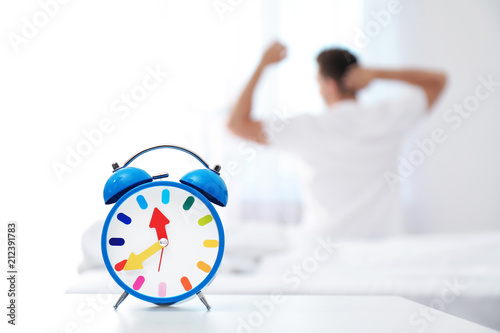Analog alarm clock and blurred man on background. Time of day