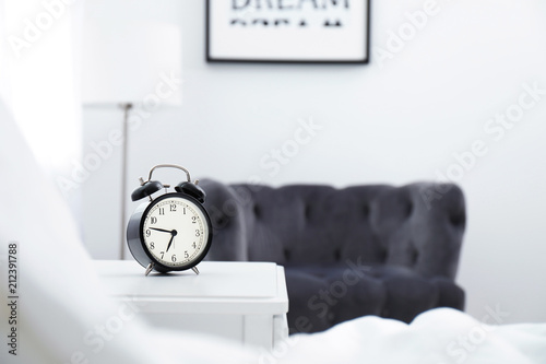 Fotografia Analog alarm clock on table in bedroom. Time of day